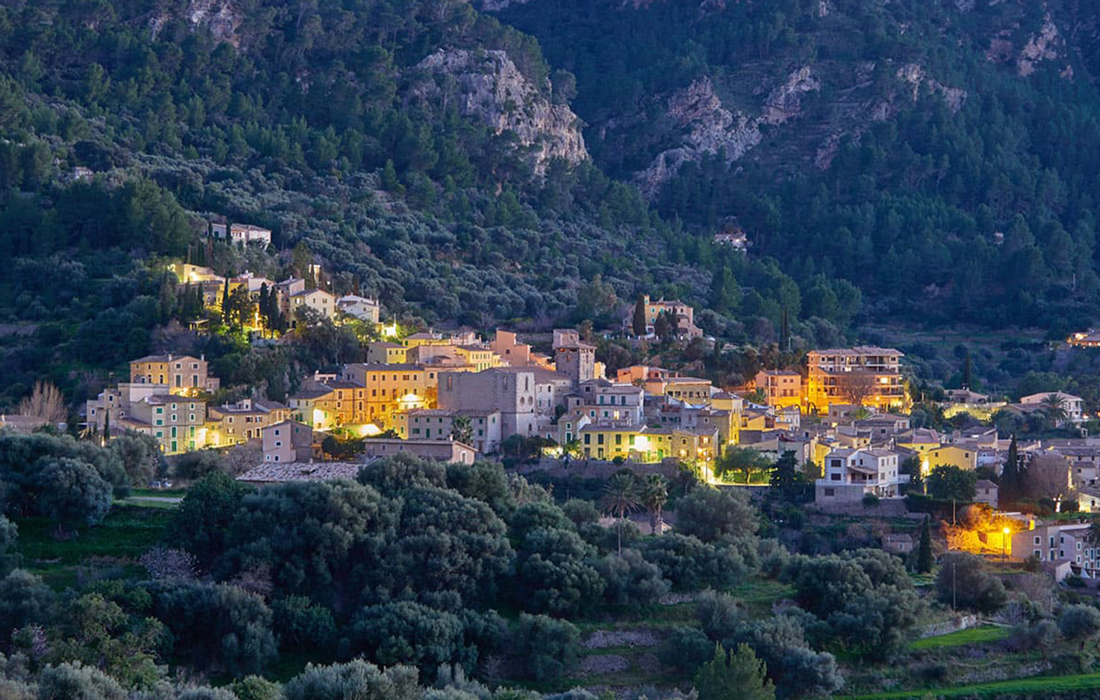 Vista panorámica nocturna del pueblo de Estellencs iluminado y envuelto por la Sierra de Tramuntana